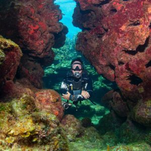 A diver is diving through a swim through in Roatan, Honduras.