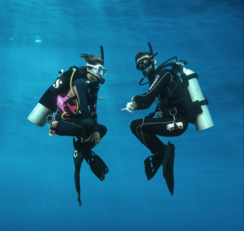 Two scuba divers practice neutral buoyancy while completing their scuba certification in Honduras. 