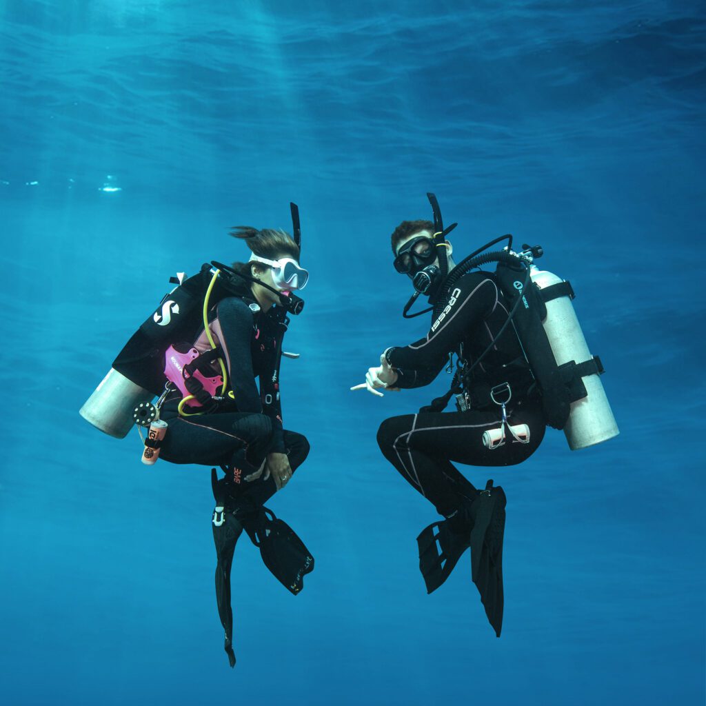 Two scuba divers practice neutral buoyancy while completing their scuba certification in Honduras. 