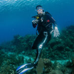 A diver dressed as a skeleton poses under water during a halloween event dive in roatan.