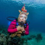a diver dressed as a unicorn poses under water during a halloween event dive in roatan.