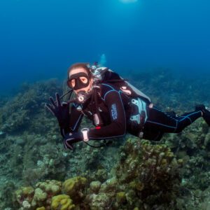A woman is scuba diving in Roatan, Honduras, and giving the okay sign for diving with her right hand.