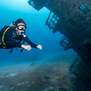 Scuba diver glides past the stern of the Aguila wreck while diving in Roatan. 