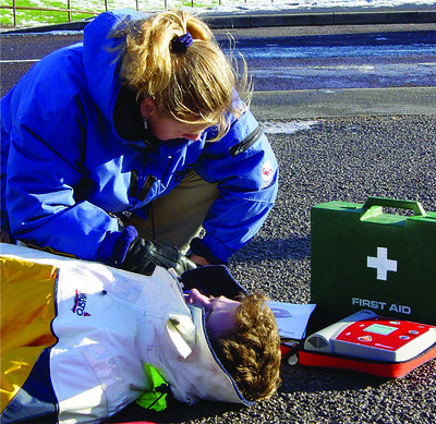 A women provides First Aid to an accident victim. This image is used to show scenarios where being an Emergency First Responder (a prerequisite to the PADI Recuse course) is valuable.