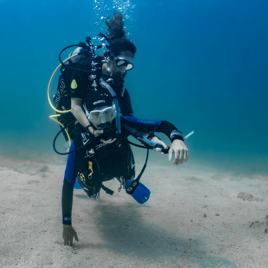 Two divers role play a diving emergency as part of the rescue diver scuba certification in honduras.
