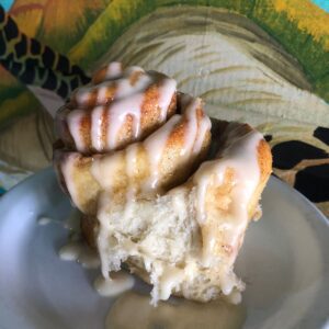 An extra large cinammon roll drizzled with icing sits atop a plate at Sandy Buns Restaurant in Roatan
