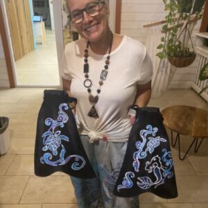 A woman holds up her painted Scuba fins in her hands and smiles.