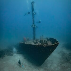 Front shot of the Aguila shipwreck in Roatan. Shows divers circling around its fully intact mast on a wreck dive in Roatan.