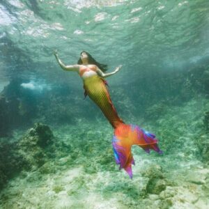 PADI Mermaid instructor Alanna ascends to the surface with her pink, purple and orange tail tailing behind her