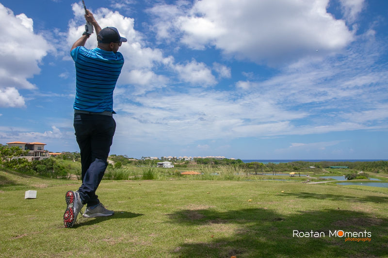 View from behind a golfer swinging at Pristine Bay Roatan 