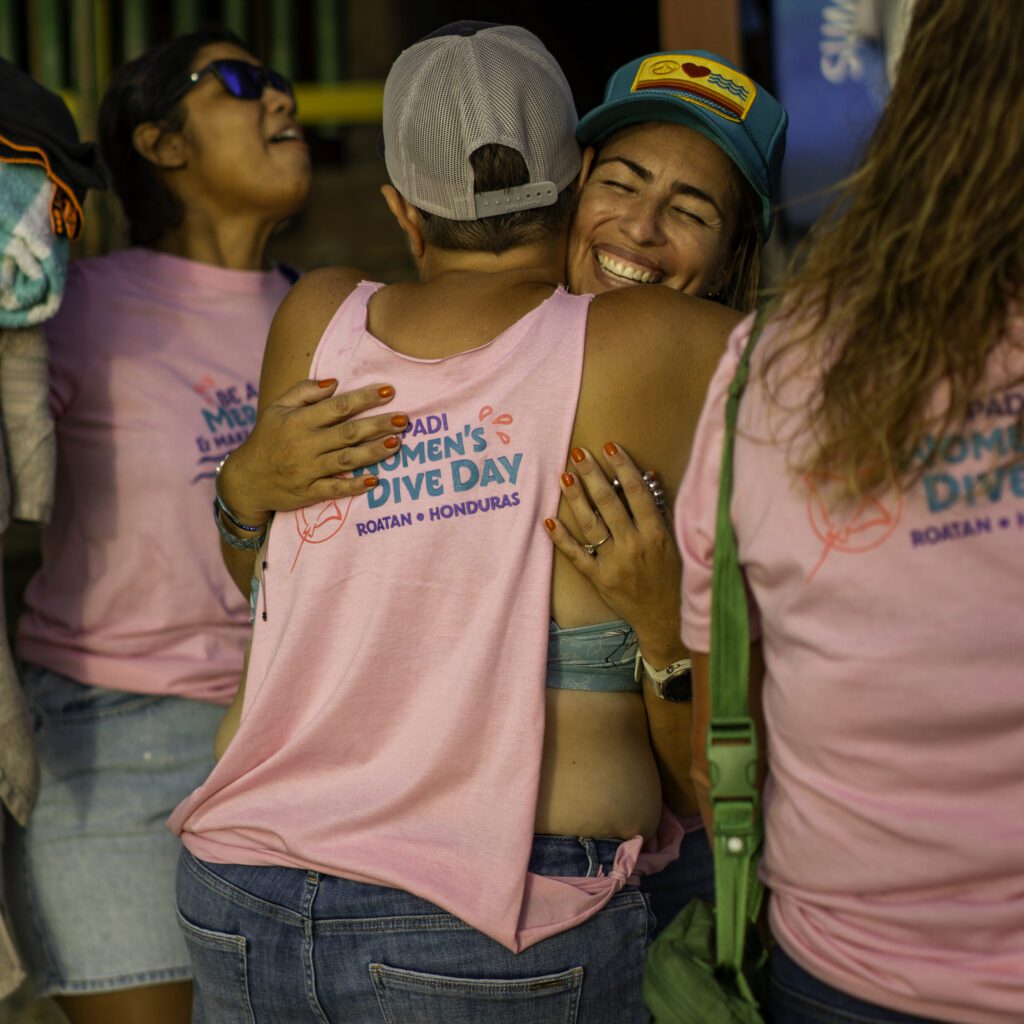 Two women embrace at PADI Women's Dive Day in Roatan at Sun Divers