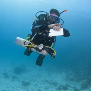 A self reliant diver with a pony bottle, checks his dive computer during the Self-Reliant Diver course.