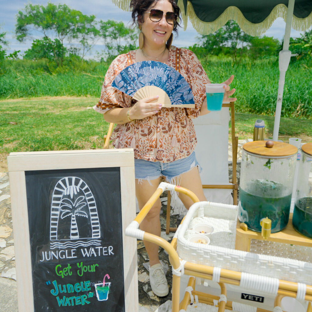 A woman stands fanning herself at the Jungle Water golf hold experience